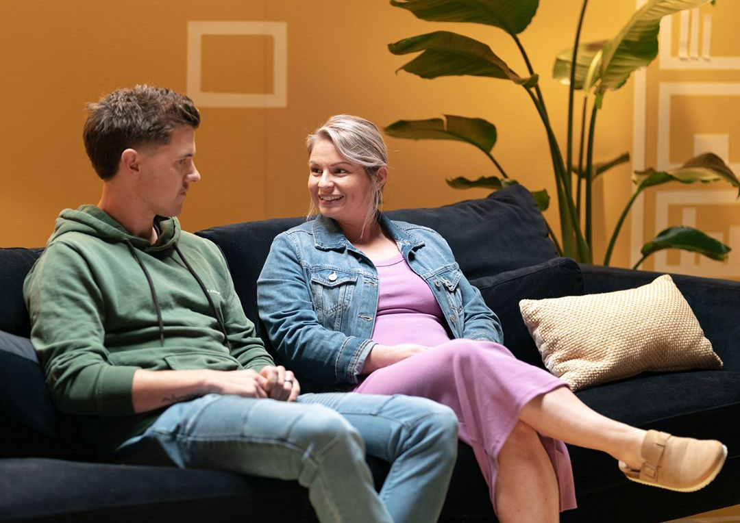 Man and woman sitting next to one another on a couch having a conversation