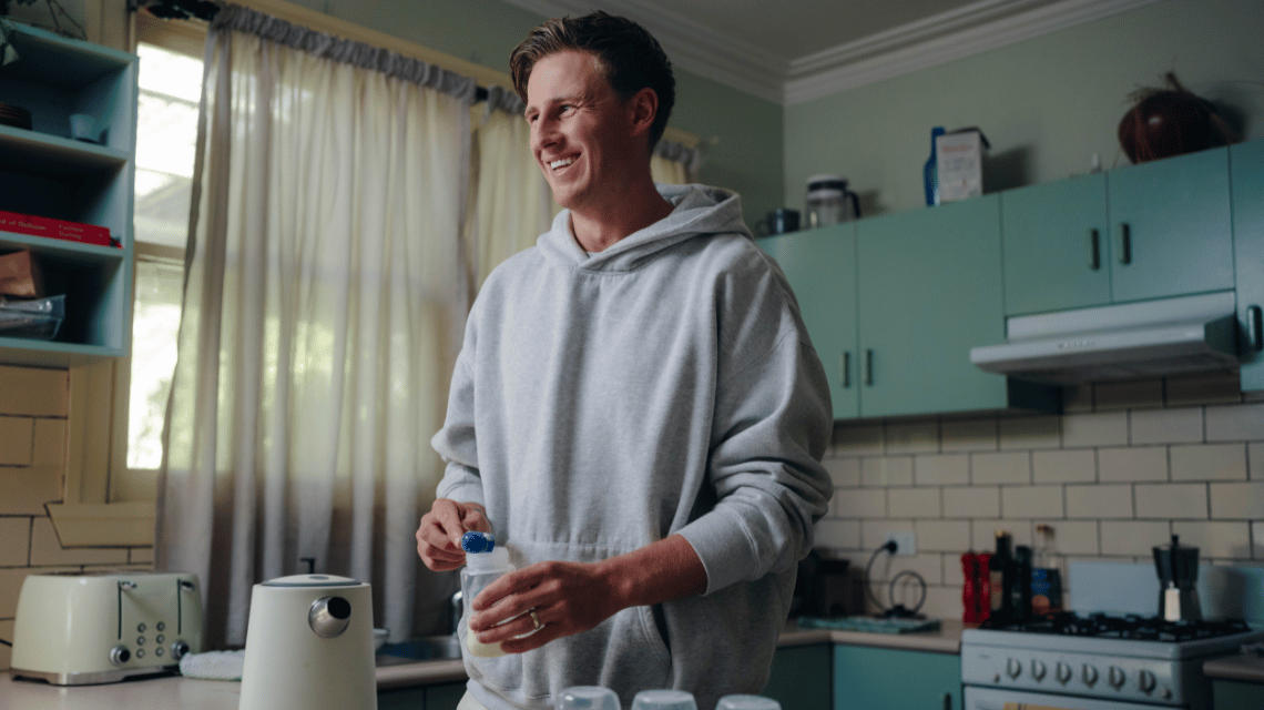 Adam, a What Kind of Man Do You Want to Be participant, prepares a baby's bottle in his kitchen.