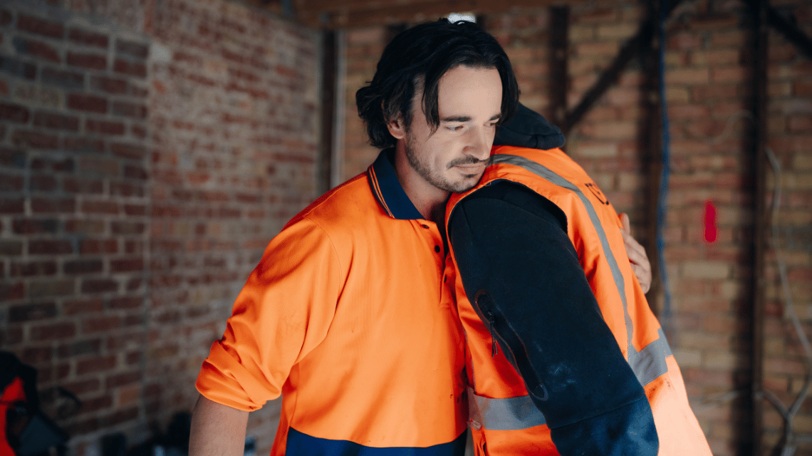 Jack, a What Kind of Man Do You Want to Be participant, hugs a workmate. They are on a building site.
