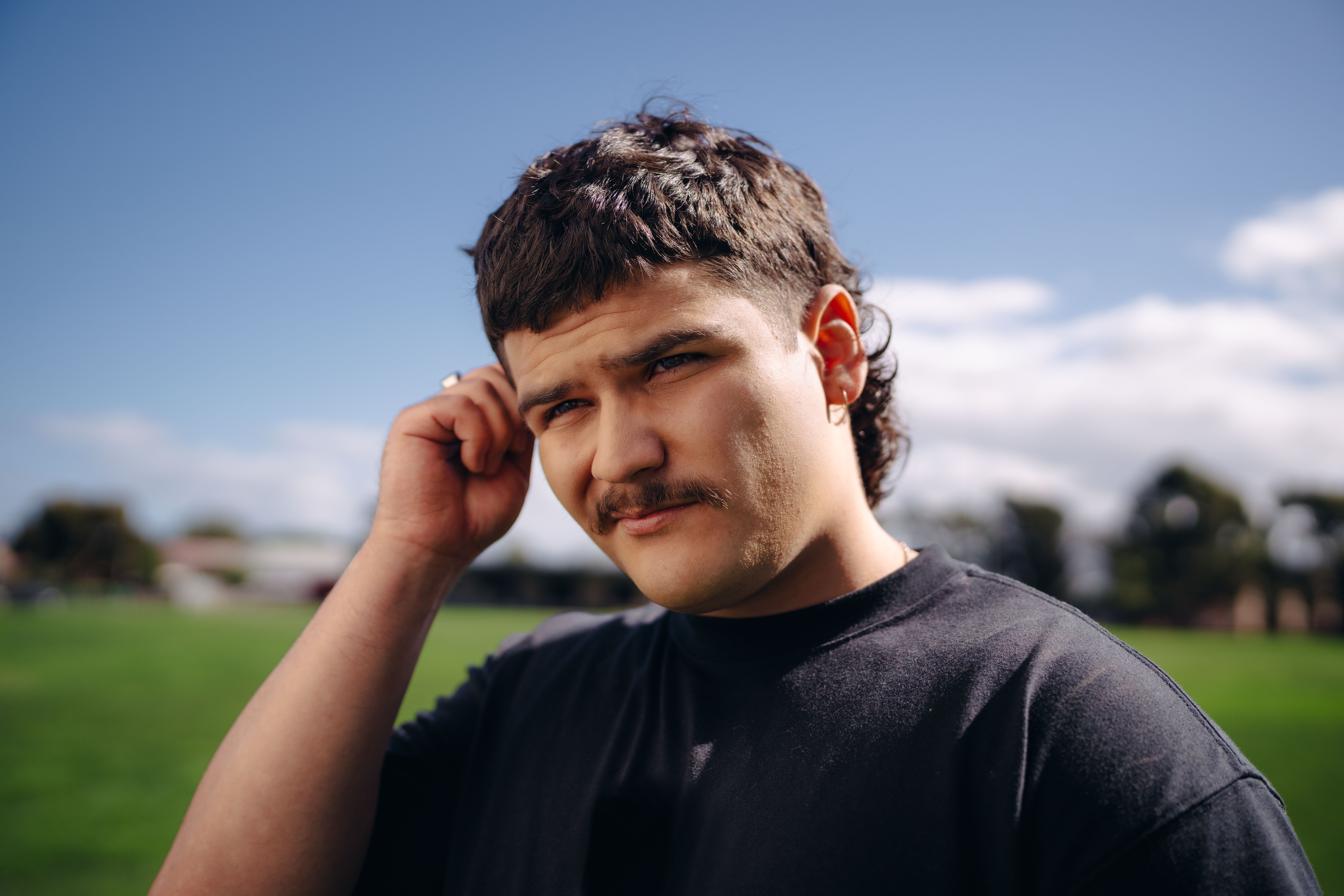 Young man standing on a football field holding the side of his face for the What Kind of Man Do You Want to Be? campaign.