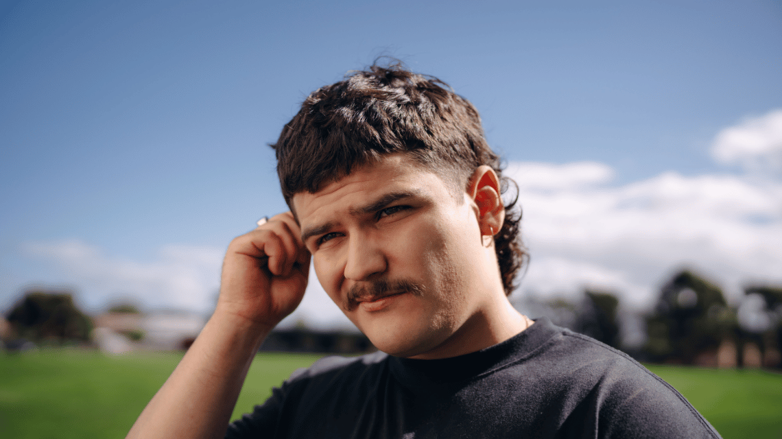 Young man standing on a football field holding the side of his face for the What Kind of Man Do You Want to Be? campaign.