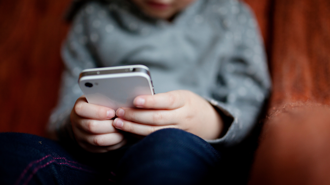 Child using a mobile phone, their face obscured