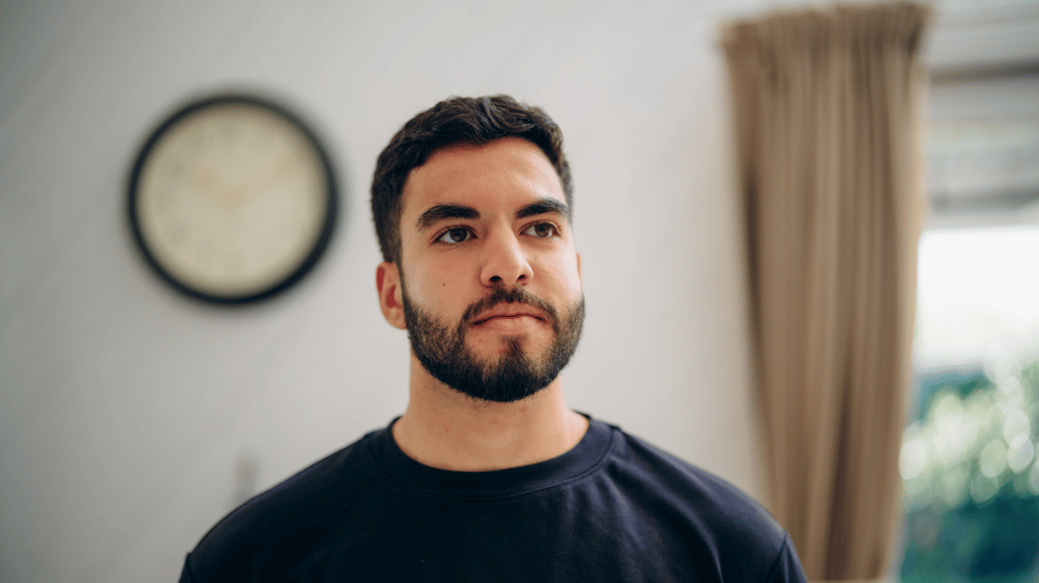 Portrait of a man in a black t-shirt standing indoors
