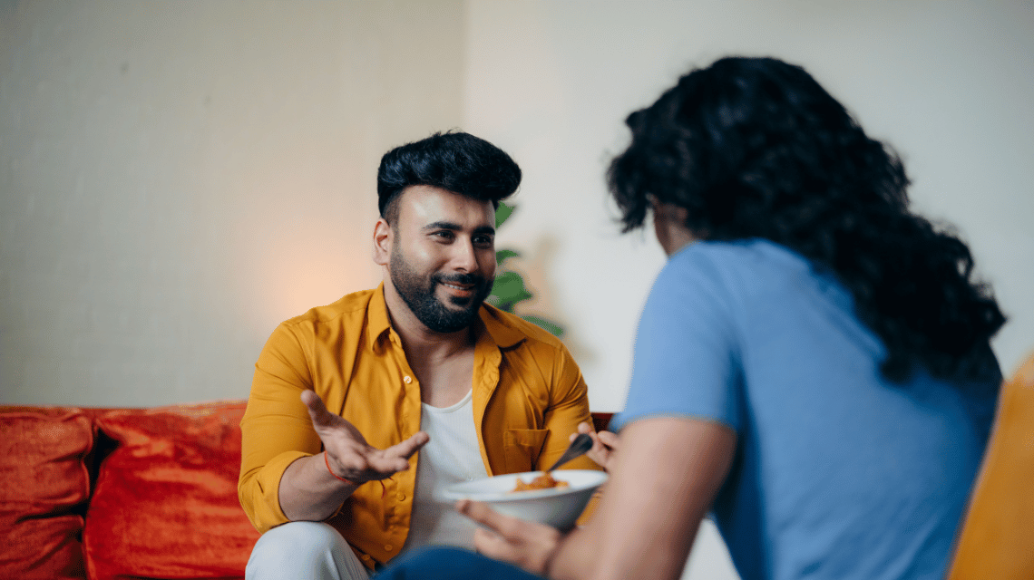 Two men sit in a loungeroom and chat.