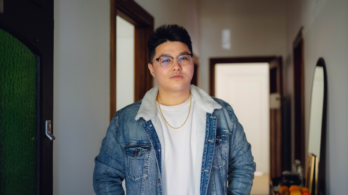 Portrait of a man in a denim jacket, standing in the entryway of a home
