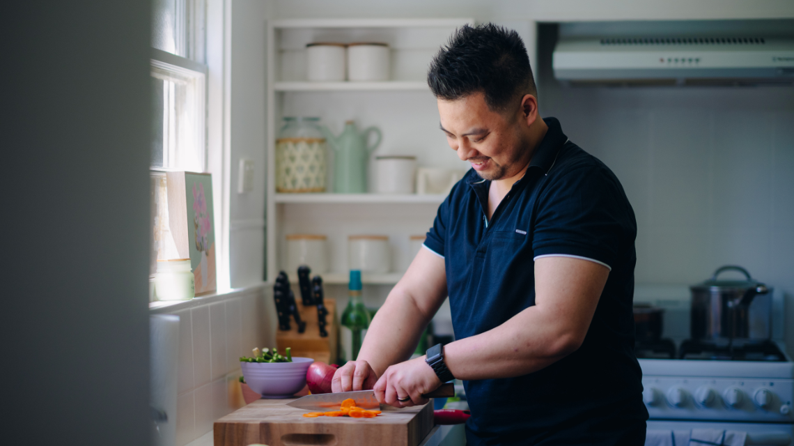 A man prepares vegetables in a home kitchen. He looks down at his work.