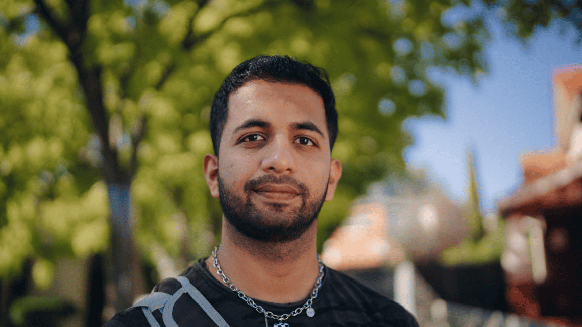 Portrait of a man in a black t-shirt, standing in a park.