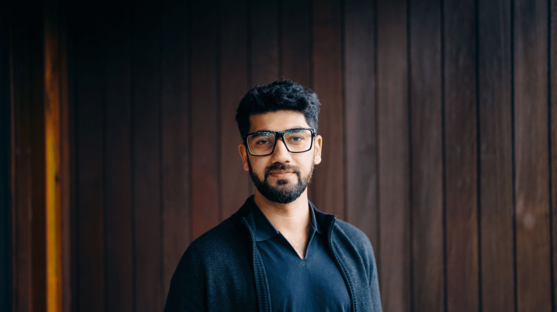 Portrait of a man in a black shirt and glasses.