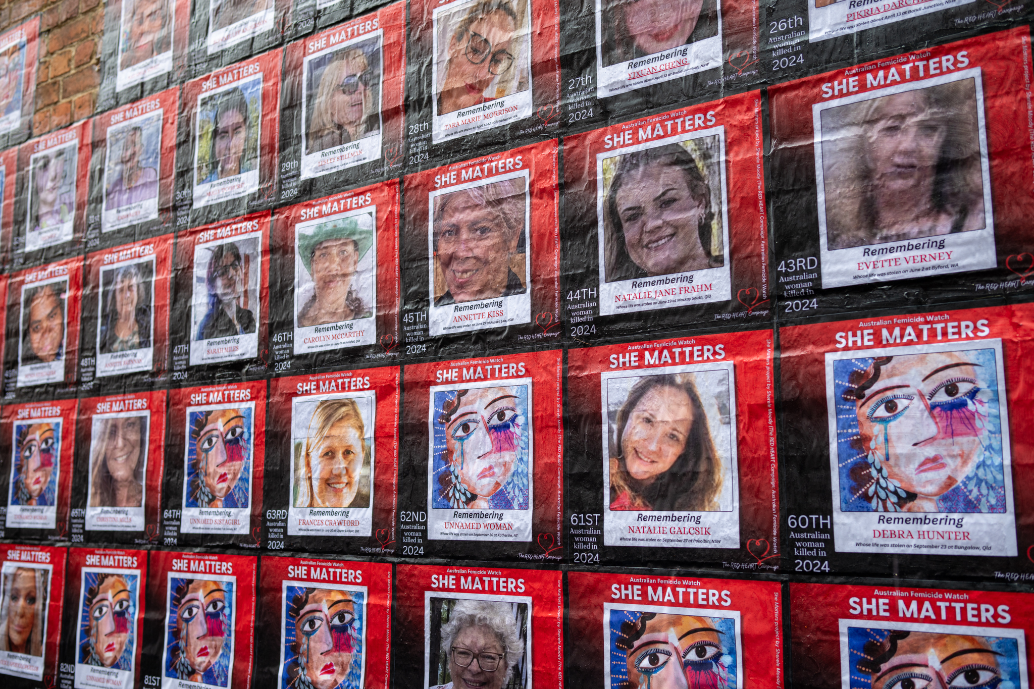 Photographs of women killed pasted in lines onto a brick wall