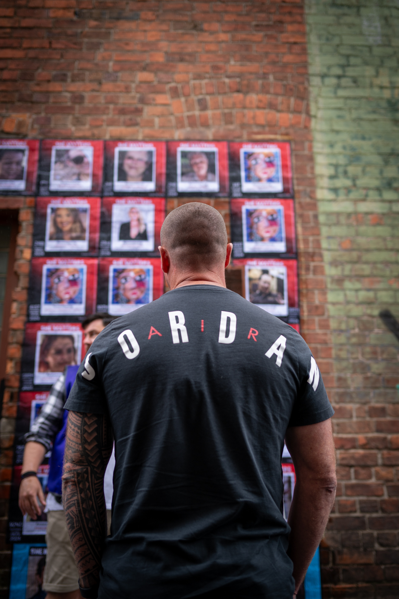 A family member looks on at photos of the women on the mural